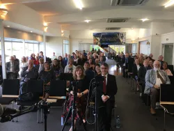 a large group of people sitting in church services viewed from the front of the room