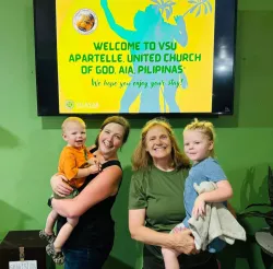 two women each holding a small child under a digital welcome sign