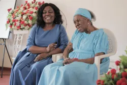 two women sitting indoors wearing blue dresses