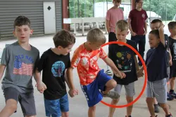 Kids holding hands walking through a hula hoop