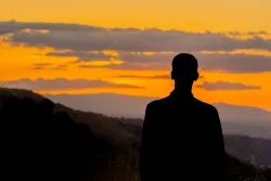 A person looking over a valley at sunset.