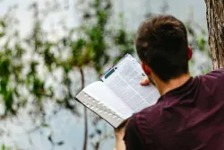 a man reading a Bible outside
