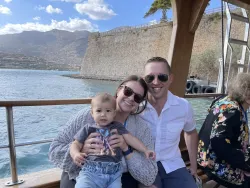 a young couple with baby sitting by a railing overlooking the water