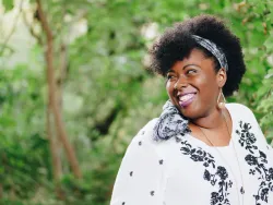 a smiling woman with trees in the background