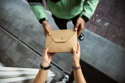 The hands of one person giving an envelope to the hands of another person
