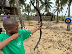 a boy aiming a bow and arrow at a target 