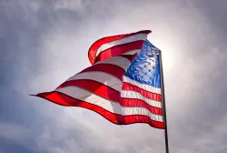 Looking up toward the sky with an American flag flying in the wind.
