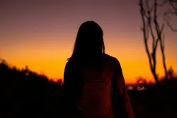 The silhouette of a woman with a red sky in the background.