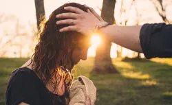 A minister laying hands on a women's head and praying after water baptism.