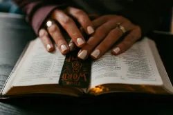 a woman's hands resting on an open Bible