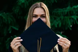 a woman holding up a graduation hat