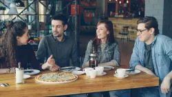 A group of young adults talking at a restaurant.