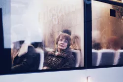 A woman sitting in a bus looking out the window.