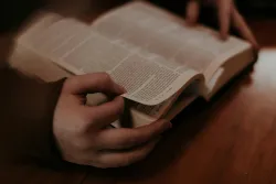 A person holding an open Bible.