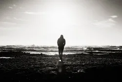 A main walking by the ocean shoreline.