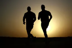 silhouettes of two men running