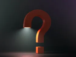 a 3-D orange question mark standing on the floor against a dark background