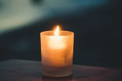 a yellow candle on a wooden table