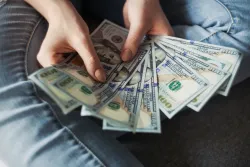 a sheaf of 100-dollar bills held in a woman's hands