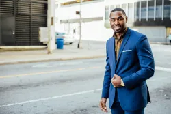 a man wearing a business suit walking in a city road