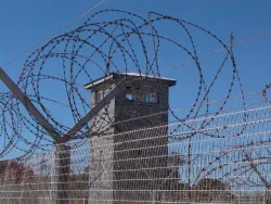 Barbed wire fence and tower in a prison yard.