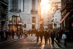 People walking a crowded city street and sidewalk.
