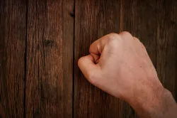 A close fist knocking on a door.
