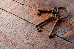 Three old skeleton keys laying on an old wood table.
