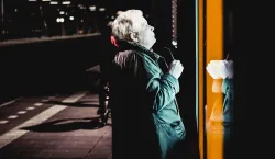An older person looking into a store window at night.
