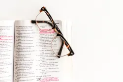 Photo of glasses sitting atop an open Bible.