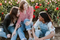 Group of three girl friends sitting together, smiling and enjoying each other's company.