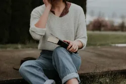 A woman sitting on the ground holding a Bible.