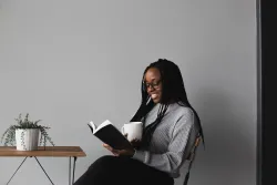 a woman holding a coffee cup and reading a Bible