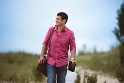 a smiling man carries a Bible as he walks