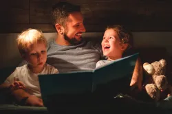 A father reading a book to his kids.