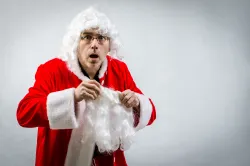 A man putting on a Santa Claus costume.