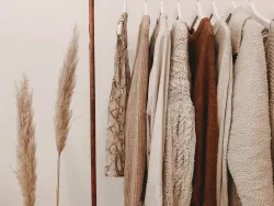 a clothing rack with several garments hanging on it and a plant to its left