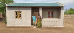two people standing outdoors in front of a small building with a green roof