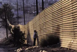 People standing by a border wall.