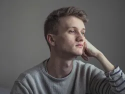 a glum-looking man looking off into the distance