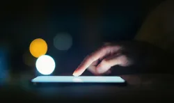 A finger touch the lit screen of an electronic device.