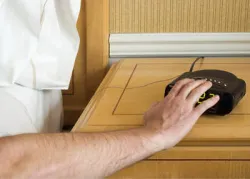 A man pressing the snooze button on an alarm clock.