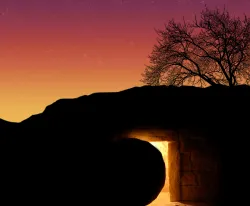 A tomb cut out of rock with a round stone next to the entrance.