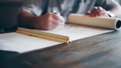 Person measuring out blueprints on a table