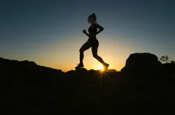 a silhouette of a running woman against a sunset