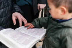 A young child touching a Bible