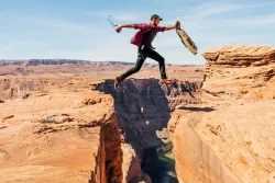 A man jumping over a cracks in rocks.