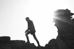 a silhouette of a man walking on a rocky surface