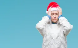A woman wearing a santa claus hat grabbing her head as if she is frustrated.