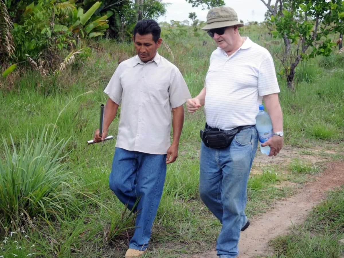 Jorge de Campos walks to a cassava field through the jungle with deacon Benedito